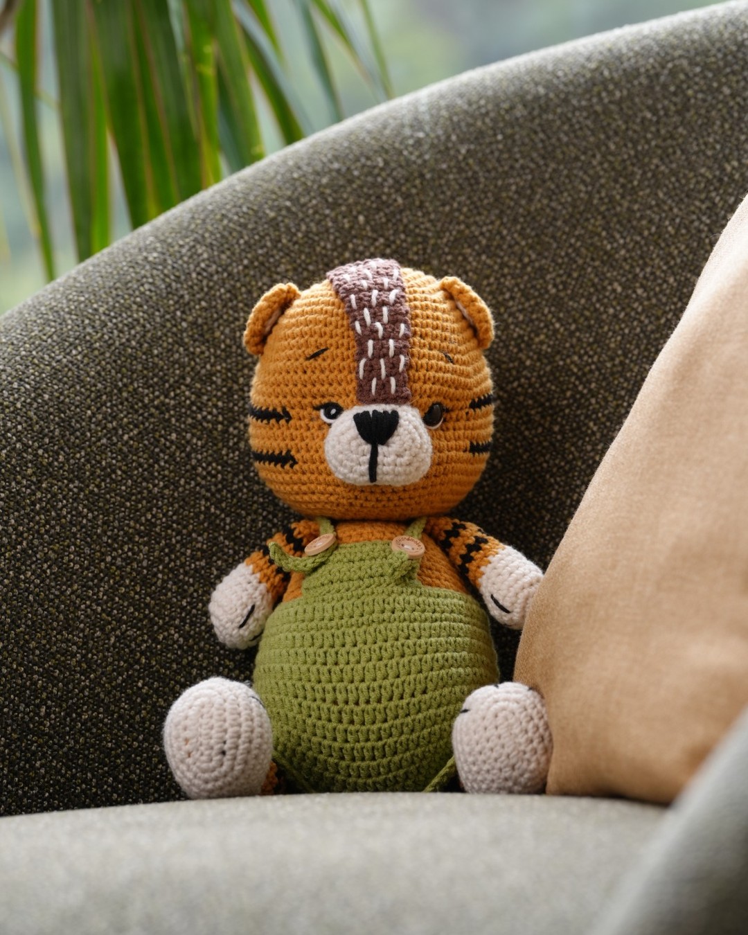 Handmade crochet Forest Bear in green overalls looking at the camera