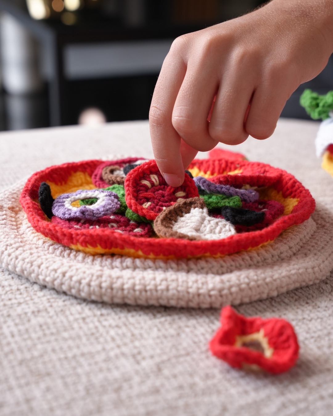 Child placing a crochet topping on the play pizza